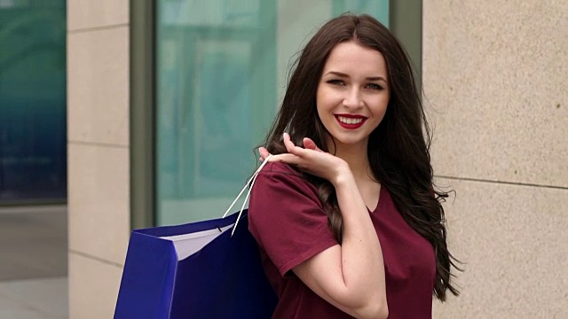 年轻女子拿着购物袋走在城市里。视频下载