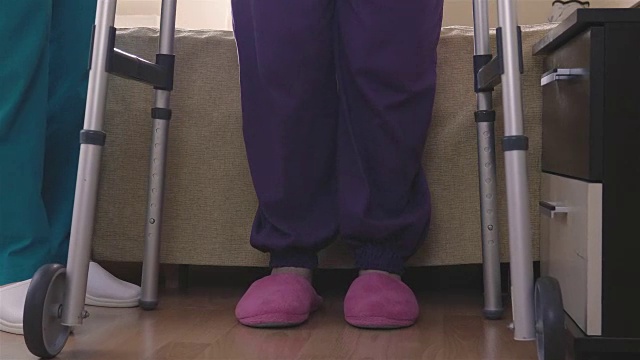 护理人员帮助老年妇女站起来并使用助行器行走视频下载