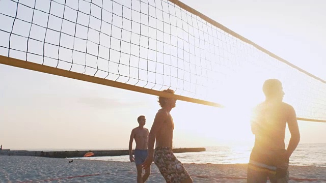 一群人在日出或日落时打沙滩排球视频下载