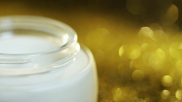 以透明质酸为基础的金色高品质敏感肌肤嫩肤美容霜，在背景中加入黄金颗粒。美丽的概念和财富的美肤霜视频素材