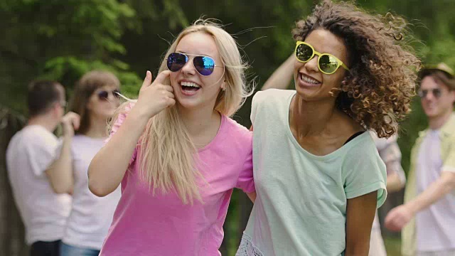 学生们在公园里举行聚会，两个美丽的多种族女孩在跳舞，微笑视频下载