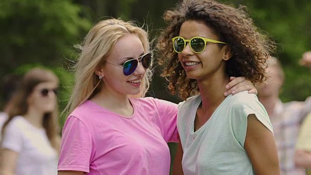 年轻漂亮的女人戴着黄色的太阳镜和朋友们跳舞，在公园里放松视频下载