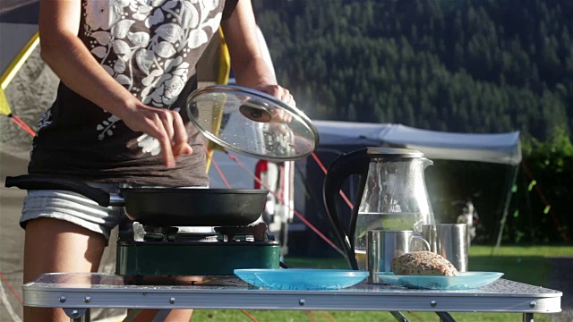 一个女人在野营时煮鸡蛋当早餐视频素材