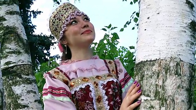 穿着民族服装的俄罗斯女孩梦想着桦树视频素材