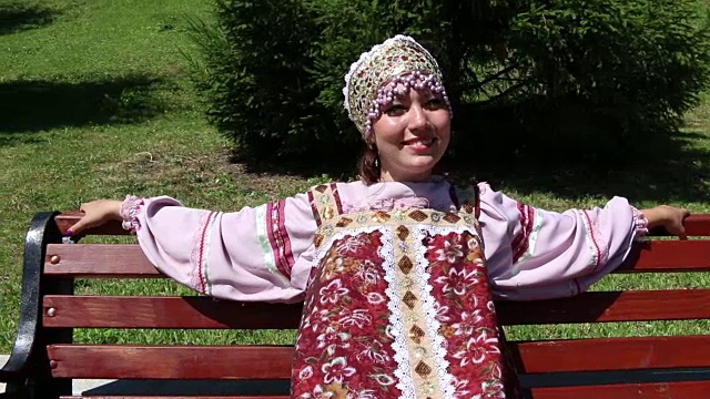 女孩坐在长椅上，穿着俄罗斯民族服装视频素材
