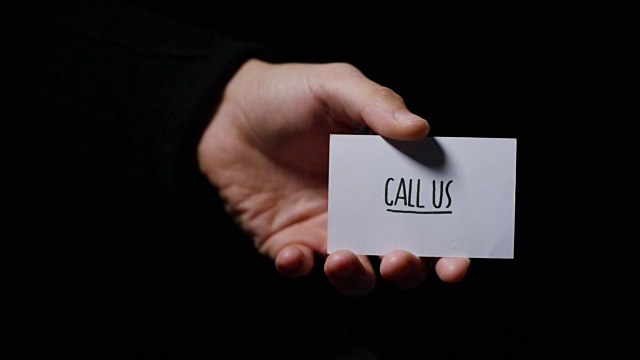 一只手举着一张卡片，上面写着“打电话给我们”。经营理念，感谢，记录网站，客户服务，沟通，业务联系。视频素材