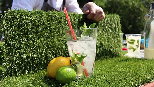 鸡尾酒不含酒精附近的工作调酒师在公园的背景上滑动视频素材