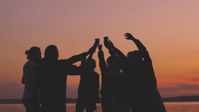 慢镜头剪影群年轻的跳舞的人们欢呼和有一个聚会在海滩上日落视频下载