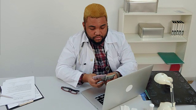 年轻的美国黑人男医生在他的桌子前数钱视频素材