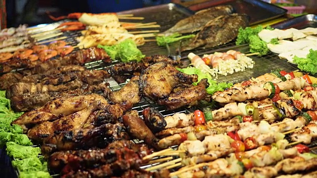 传统的亚洲肉沙茶街头小吃晚上在户外烹饪。东南亚视频下载