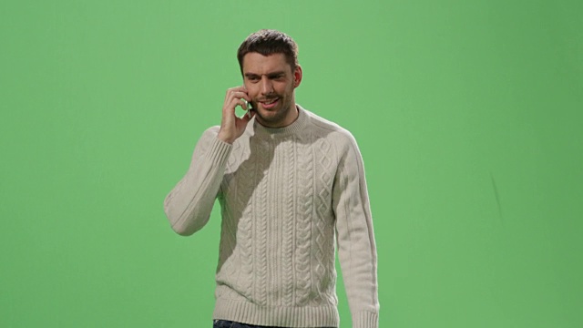 一个随意的白人男子正在一边走一边讲电话，背景是一个绿色的模拟屏幕。视频素材