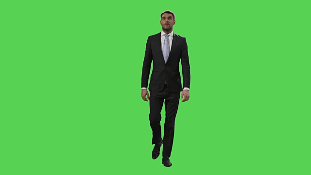 一位西装革履的商人走在绿色屏幕模型的背景上。视频素材