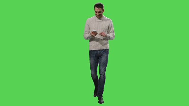 一个随意的白人正在走路，在绿色屏幕上使用智能手机。视频素材