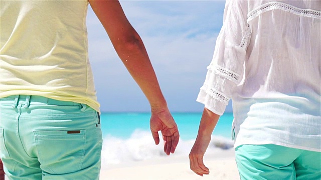 一对年轻夫妇在热带海滩上牵着手。慢镜头特写镜头视频素材