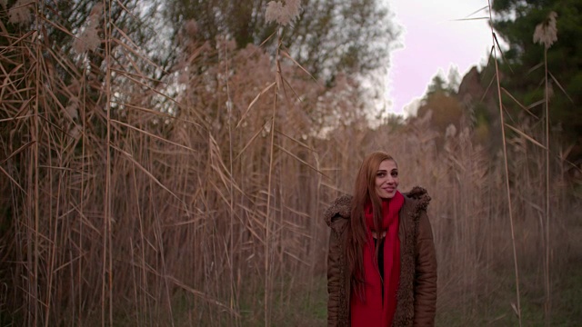 年轻的红发姑娘微笑着站在秋天的田野里视频素材