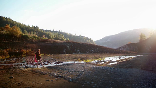 年轻漂亮的红发姑娘赤脚在山河溪里玩耍视频素材
