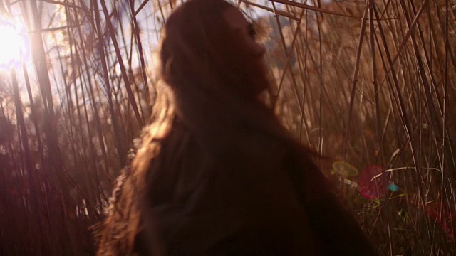 日落时分，一个长着红头发的年轻女子在田野里视频素材