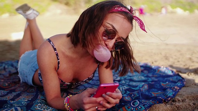 一个年轻女人在沙滩上吹泡泡发短信视频下载