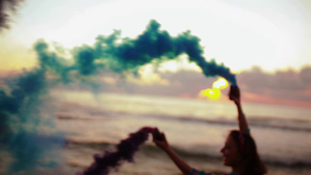 日落时分，年轻女子背着烟雾弹在海滩上奔跑视频素材