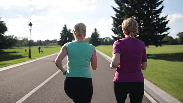 在公路上跑步的老年健身妇女的后视图视频素材