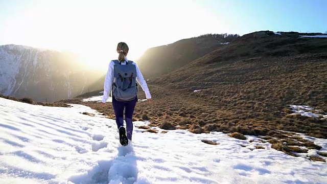 日落时分，一个女人走在冬日的山间小路上视频素材