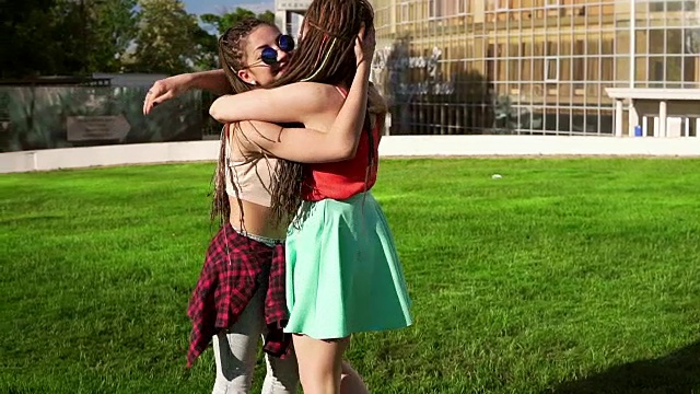 两个快乐的小女孩抱在一起。在阳光明媚的公园里，兴奋的女性朋友们互相拥抱、欢笑。女人的友谊。Slowmotion拍摄视频素材