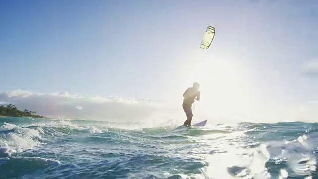日落时分，一名年轻人在蓝色的海洋中骑着冲浪板风筝冲浪视频素材
