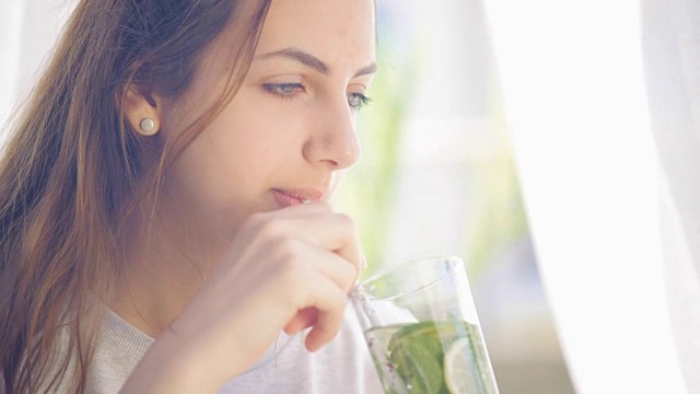 年轻女子喝着柠檬薄荷排毒水。视频素材