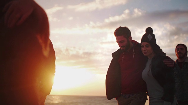 日落时分，一对年轻夫妇和朋友在海滩上散步视频素材