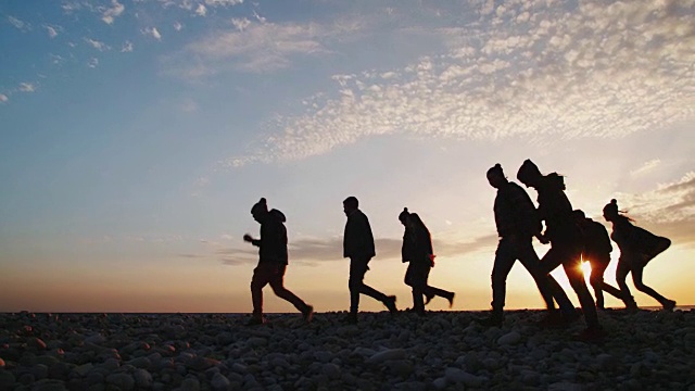 日落时分，一群朋友在海滩上散步视频素材