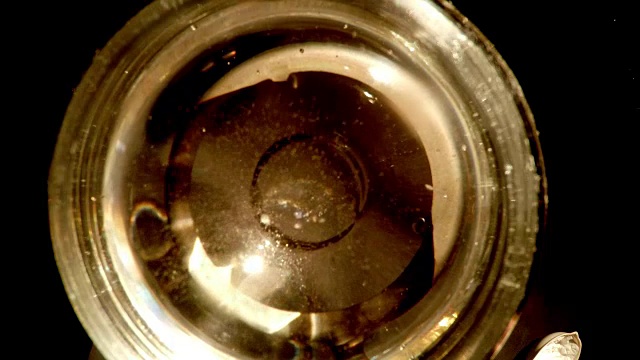 在玻璃烧瓶中，手撒苏打水后，积极的泡泡上升

黑色背景视频下载