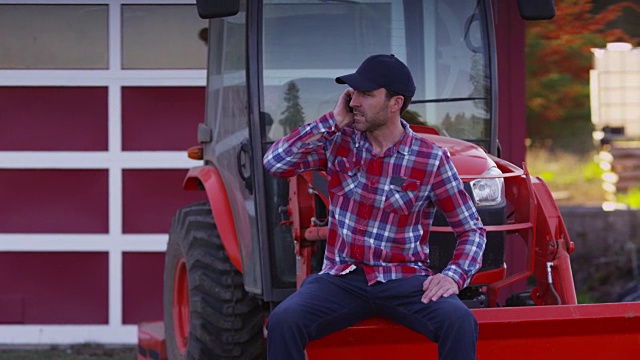 农夫坐在拖拉机上用手机视频素材