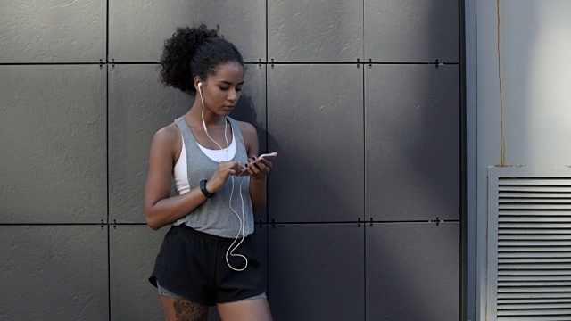 年轻的运动女性在户外使用智能手机视频素材