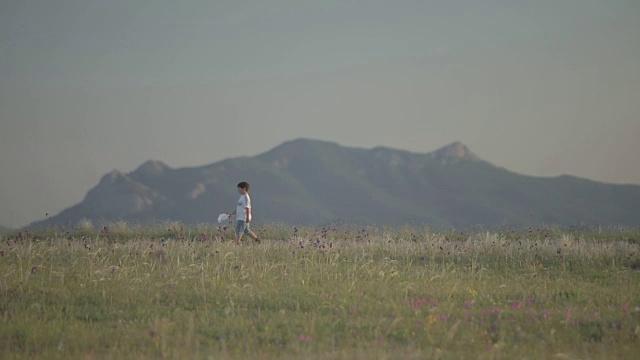 手里拿着手帕的男孩映衬着群山的背景视频素材