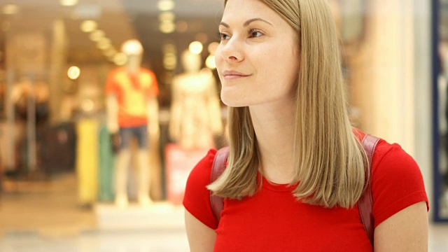 年轻美丽迷人的女人站在购物中心，微笑着。购物消费的概念视频素材