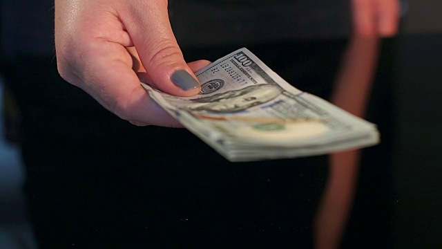 特写的女孩给了男人一叠美元。视频素材