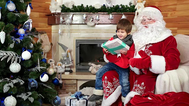 圣诞老人欢迎小男孩，小朋友拿到圣诞礼物就坐在圣诞老人的腿上，给小朋友送礼物视频素材