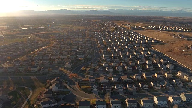 鸟瞰图:日出时被群山包围的山谷郊区小镇的排屋视频素材