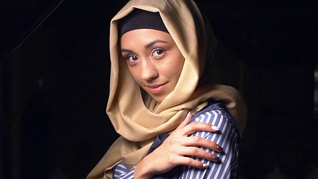 穿着传统穆斯林服装的漂亮女孩的肖像。戴着头巾的女孩看着镜头微笑着。慢动作视频下载