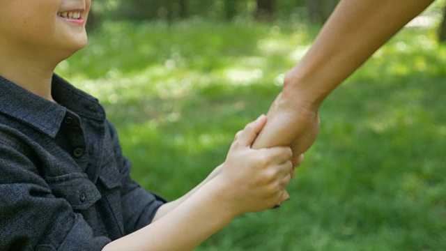 微笑的孩子拉着妈妈的手，要求和他一起在公园里玩视频下载