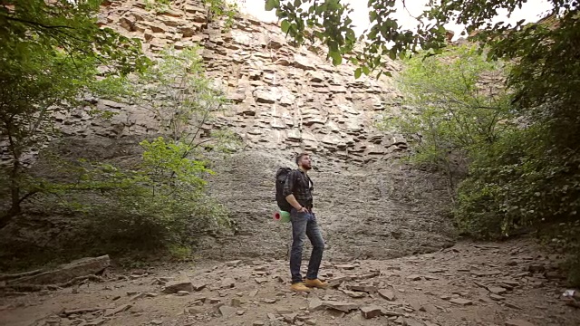 背着背包的男子徒步旅行，背景是岩石。视频素材