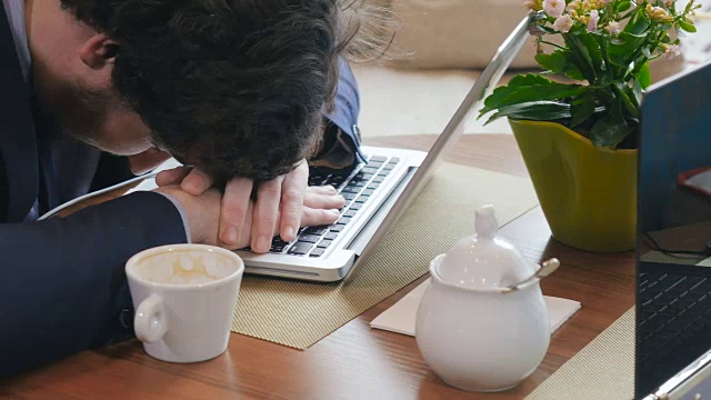 一个男人的肖像斜着头躺在笔记本电脑的键盘上视频下载