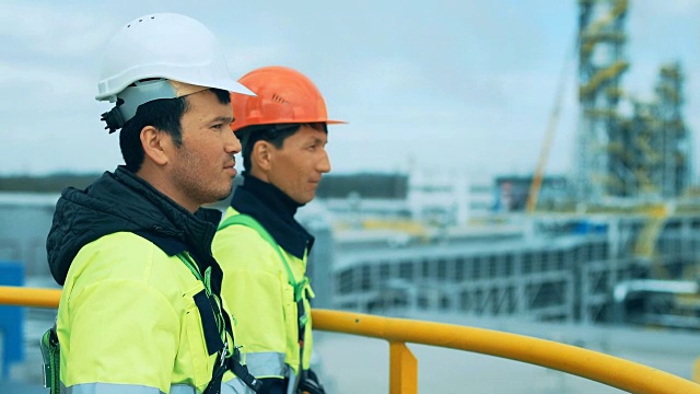 炼油厂的工程师和工人正站在塔上视频素材