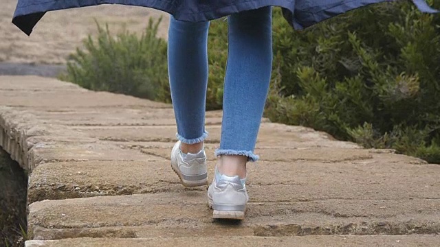 年轻女性游客背包行走在户外的石头小径。女人的腿在美丽的自然岩石地上行走。女孩在旅行中踏山。健康的生活方式。慢动作视频素材