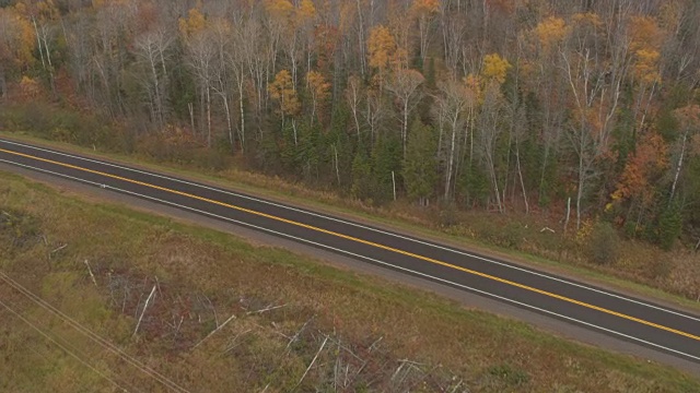 航拍:一辆SUV行驶在空旷的州际公路上，穿过秋天的落叶林视频素材