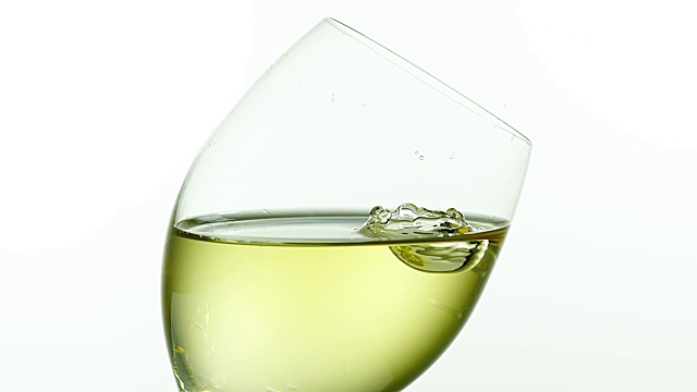 白色背景下，一滴白葡萄酒落入玻璃杯，4K慢动作视频下载