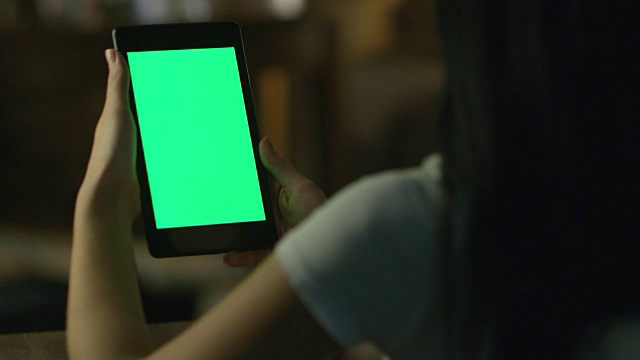 少女正在使用平板电脑与绿色屏幕在风景模式在晚上。休闲的生活方式。视频素材