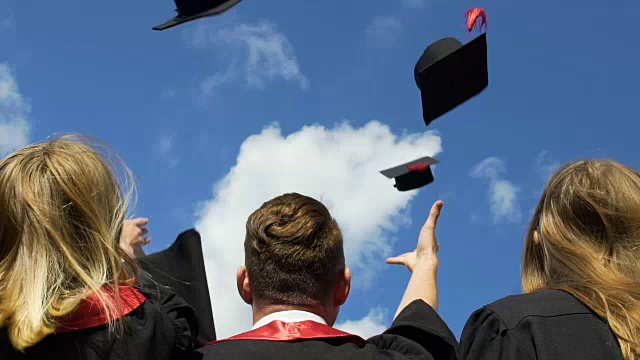 快乐的年轻人庆祝毕业，把学术帽抛向空中视频素材