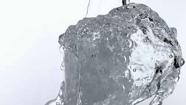水被倒进玻璃在白色背景下，慢动作4K视频素材