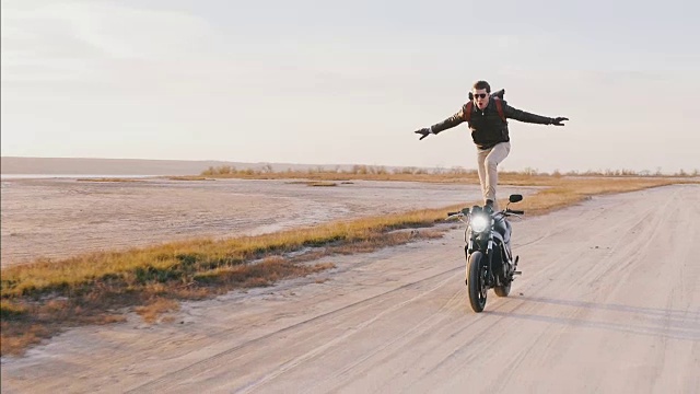 日落时分，摩托车手骑着摩托车在公路上高速冲浪，动作缓慢视频下载
